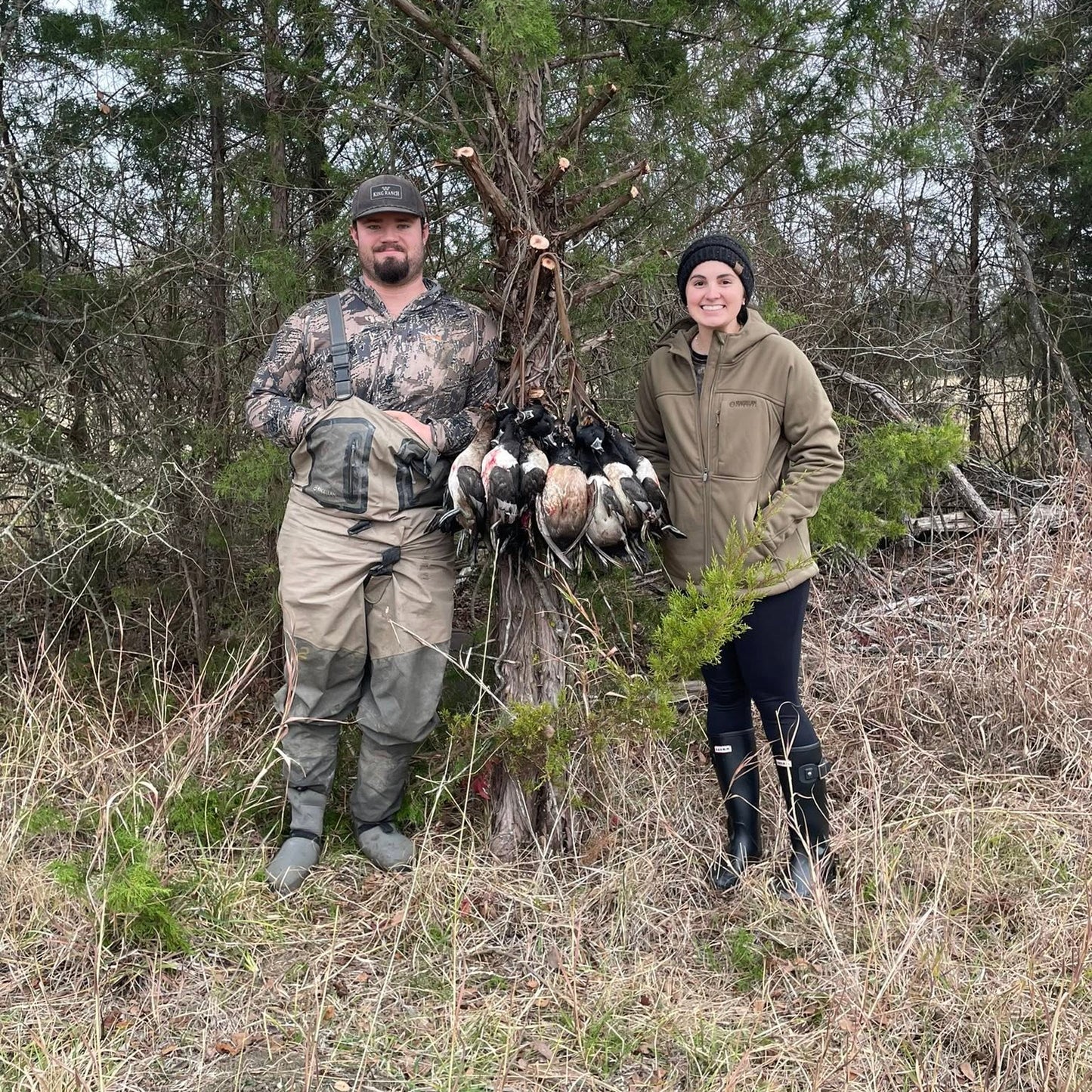 Two people standing in a wooded area with game birds. Waterfowl guide service. Texas hunting guide. Oklahoma hunting guide. Duck hunting guide Texas and Oklahoma.